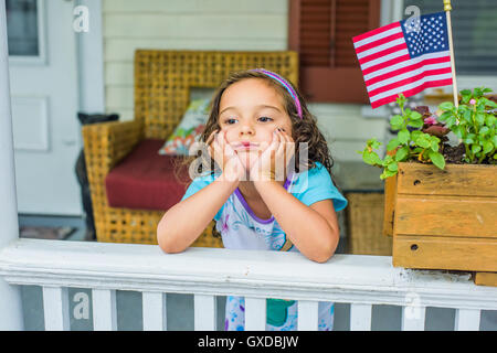 Bored girl waiting on porch on Independence Day Stock Photo