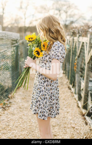 Young woman holding sunflowers, side view Stock Photo