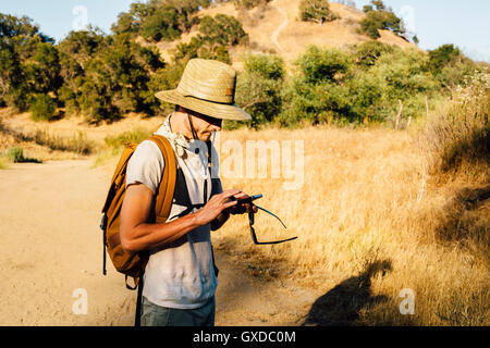Hiker looking down at smartphone, Malibu Canyon, California, USA Stock Photo