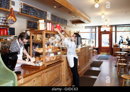 Male and female workers in bakery going about business Stock Photo