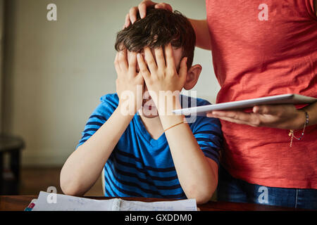 Mother comforting upset son doing homework Stock Photo