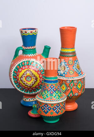 Studio shot of still life of three orange ornate pottery vases on background of black table and white wall Stock Photo