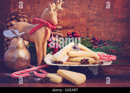 Festive Christmas holiday traditional shortbread biscuit cookies on a rustic wood table background, with applied retro vintage s Stock Photo