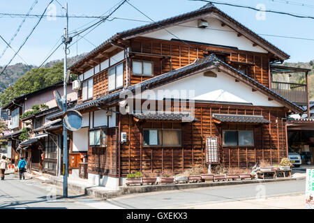 Japan, Izushi. Large two storey wooden and plaster corner house from  the Meiji period with ground floor used as a shop. Daytime, blue sky. Stock Photo