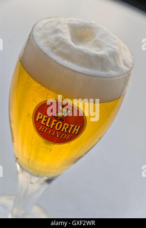 Freshly poured glass of Pelforth Blonde pale lager on cafe table brewed in Mons-en-Baroeul, France Stock Photo