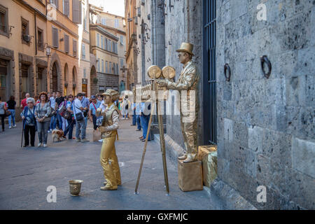 Street performers in Sienna, Italy. Street mimes acting like old time movie camera man and assitant. Stock Photo