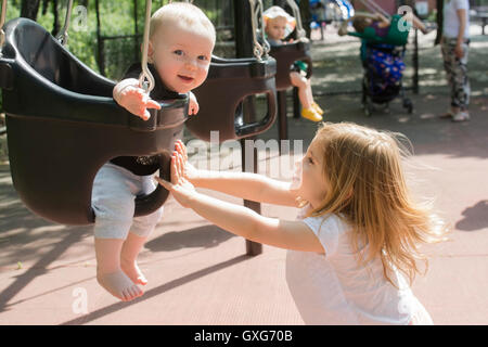 Caucasian girl pushing baby in swing Stock Photo