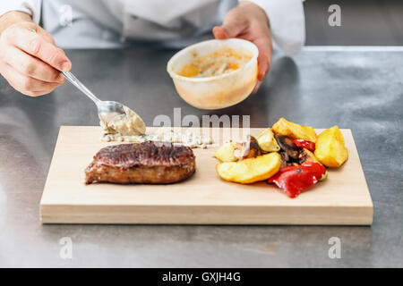 Club beef steak with pepper sauce and grilled vegetables on cutting board