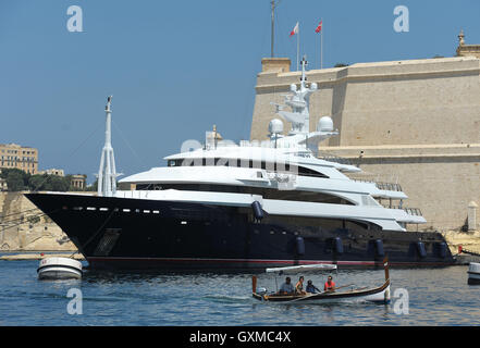 A traditional Luzzu passes a luxury superyacht in Grand Harbour Marina, Vittoriosa, Valletta, Malta Stock Photo