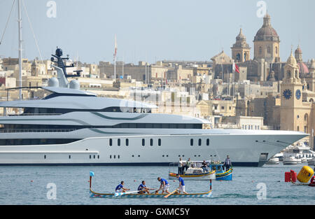 Rowing Regatta past a Luxury superyacht in Grand Harbour Marina, Vittoriosa, Valletta, Malta Stock Photo