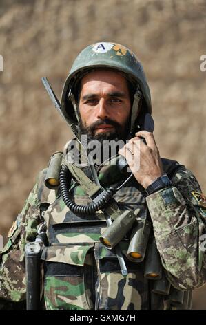 An Afghan National Army soldier uses a phone during a security patrol supporting Operation Helmand Spider February 16, 2010 in Badula Quip, Helmand province, Afghanistan. Stock Photo