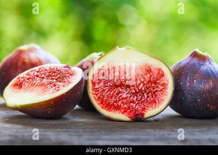 Fresh ripe black figs on rustic grey wooden table with green blurry background. Copy space Stock Photo