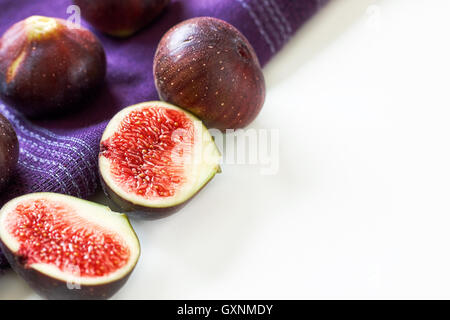 Fresh ripe black figs with purple tablecloth on white background Stock Photo