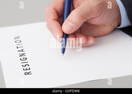 Man with a pen in the hand, writing a letter of resignation on a table Stock Photo