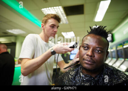 Black male has haircut shaved head at PaddyPower manchester as a PR marketing stunt Stock Photo