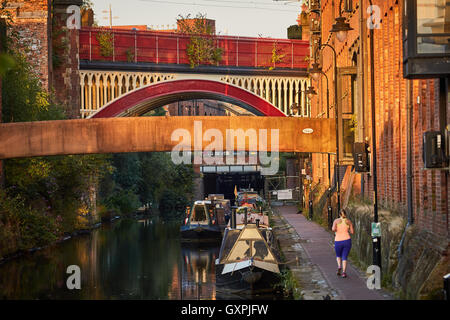 Manchester canal lock 92   locks  Castlefield canal boats jogger running towpath urban city scene golden sunshine railway bridge Stock Photo