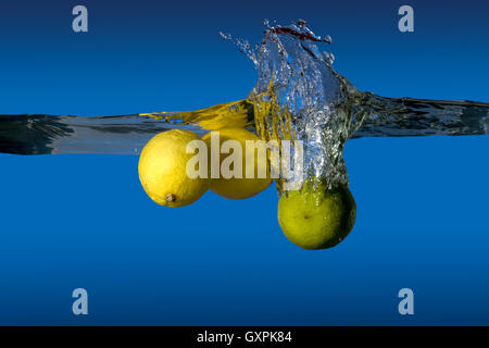 lemon and lime dropped into water holding up a lot of splashing Stock Photo