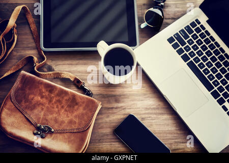 Working place: laptop, tablet, phone, cup of coffee and stylish bag on the table of a business woman, lifestyle of modern people Stock Photo