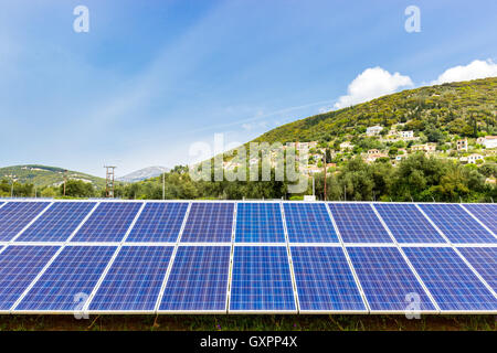 Row of blue solar collectors near greek town on mountain Stock Photo