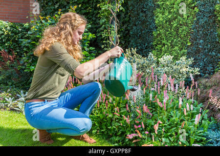 Young caucasian woman with watering can above flowers Stock Photo