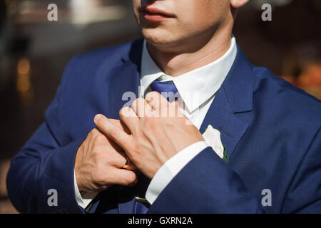 Groom in a blue suit adjusts his tie Stock Photo