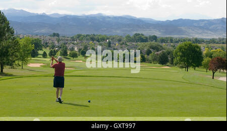 Golfer tees off at 18th hole of Indian Peaks Golf Course Stock Photo