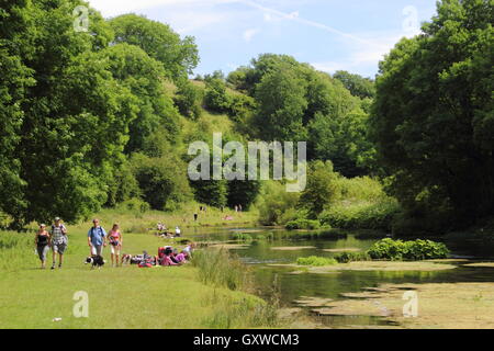 Walkers on a popular riverside route in Lathkiill Dale, a celebrated limestone dale in the Peak District, Derbyshire England UK Stock Photo