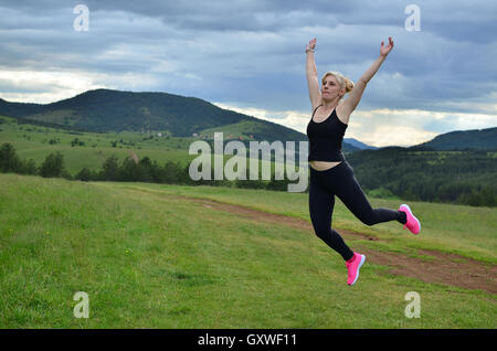 full length view of happy woman in grey leggings and green sports