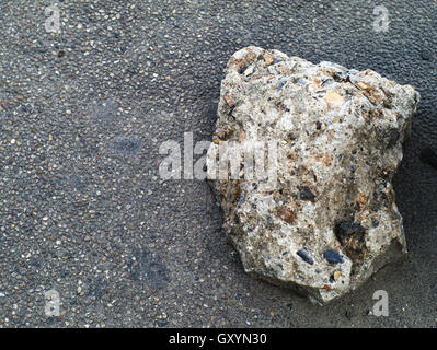 right-aligned small brick made of stones and pebbles on asphalt background Stock Photo