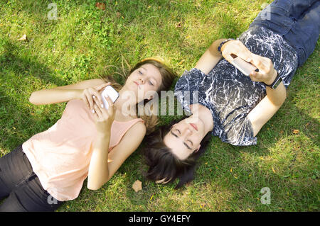 Friends at the park together using smart phones. Stock Photo