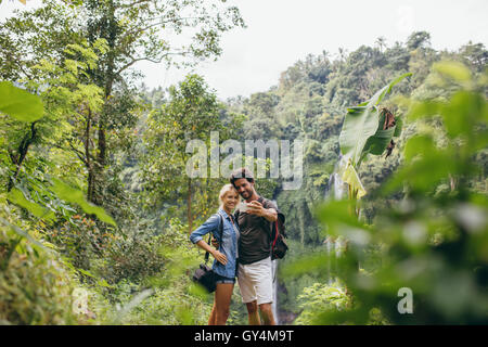 Young tourists taking selfie in the forest. Man and woman in forest taking self portrait with their cellphone. Stock Photo