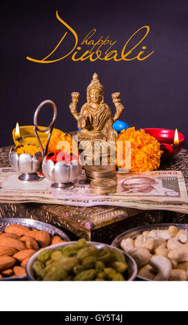 Happy Diwali Greeting card showing oil lamp or diya with crackers, sweet or mithai, dry fruits, indian currency notes, flowers Stock Photo