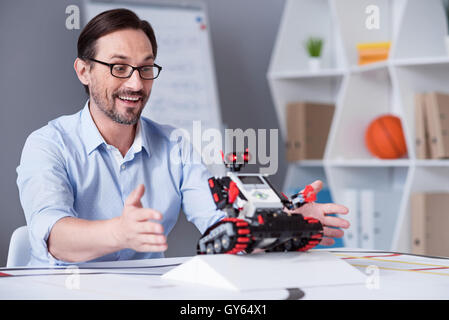 Excited man testing a little red robot Stock Photo