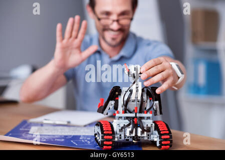 Joyful engineer testing robot. Stock Photo