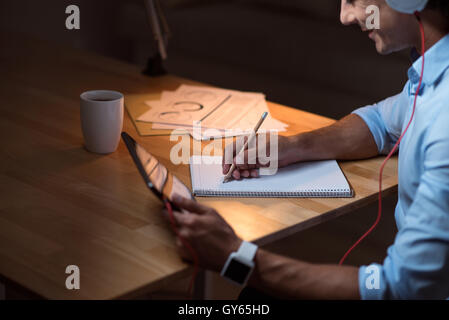 Pleasant smiling man writing on note book. Stock Photo
