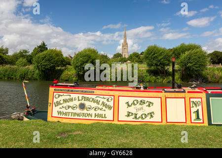 A narrow boat moored on the River Thames opposite the parish church of St Lawrence at Lechlade, Gloucestershire, England, UK Stock Photo