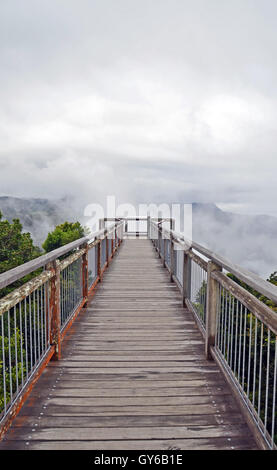 Ethereal Wooden walkway bridge leading into low cloud above mountains in Dorrigo National Park, New South Wales, Australia Stock Photo