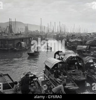 1950s, historical, a view from this era across the Aberdeen floating village in Hong Kong showing the junks (boats) moored on the water and people aboard them. The people living on the junks in Aberdeen were known as Tanka, a group in southern china who traditionally used their boats for fishing and for living on. Stock Photo