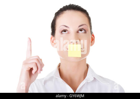 Beautiful woman with empty card on lips, pointing up. Stock Photo