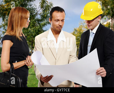 Married couple and architect looking to the blueprint and discussing about the house construction plan Stock Photo