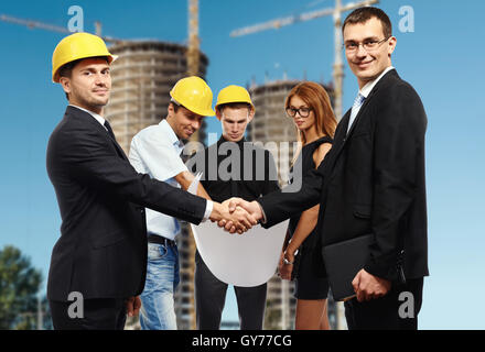 Business people shaking hands, finishing up a meeting against construction site Stock Photo