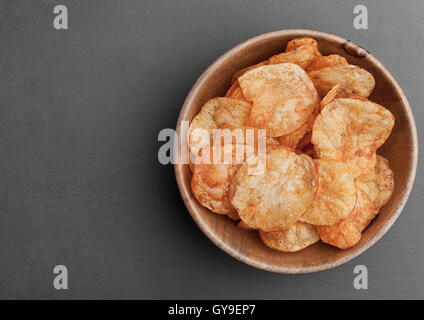 Bowl with potato crisps chips on black stone board. Junk food Stock Photo