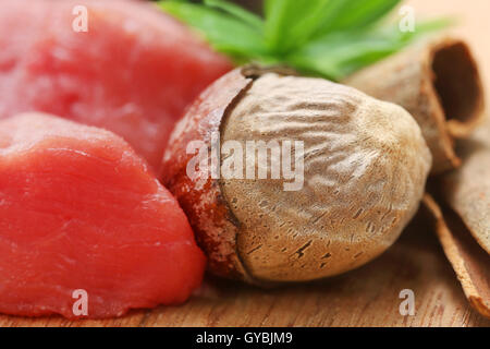 Raw beef with nutmeg other spices on wooden surface Stock Photo