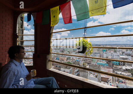 Indian man drinks coffee on a fifth floor balcony overlooking the city of Hyderabad,18 September 2016. Stock Photo