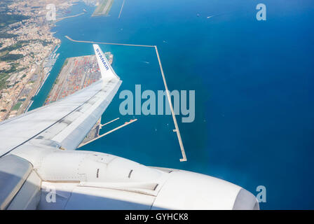 Ryanair flight leaving Genoa airport over shipping port Stock Photo