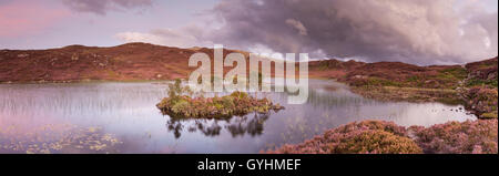 Tree island on Dock Tarn in the fells above Watendlath in the English Lake District on a later summer's evening panorama Stock Photo