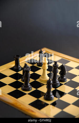 White chess pieces surrounding black king. Close view. Stock Photo