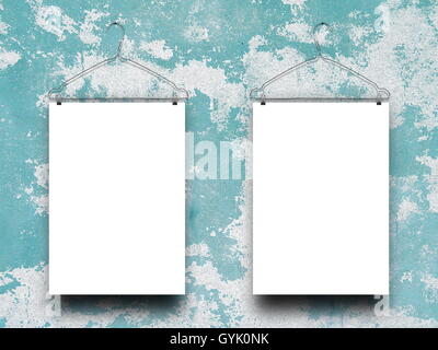 Close-up of two blank frames hanged by clothes hangers against aqua and gray scratched concrete wall background Stock Photo