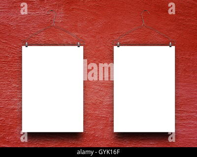 Close-up of two blank frames hanged by clothes hangers against red rough plastered concrete wall background Stock Photo
