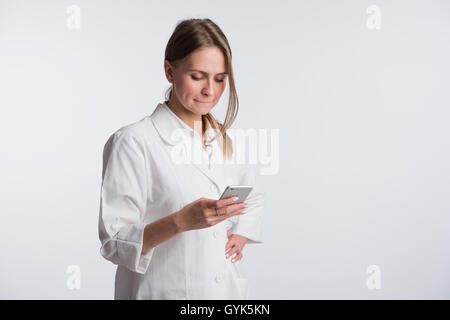 Young woman doctor holding her smartphone while smiling Stock Photo